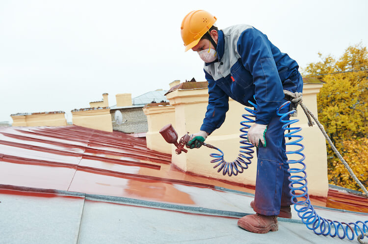 屋根を塗装する作業員